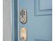 A close-up view of a modern digital lock, with the hardware and a blue door at 10437 Ebb Tide Ln, Orlando, FL 32821