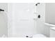 All-white tiled walk-in shower has black shower head and grab bars for accessibility at 1382 Wright St, Daytona Beach, FL 32117