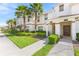 Charming townhome exterior featuring lush landscaping, palm trees, and inviting front entrances with covered porches at 1569 Plunker Dr, Davenport, FL 33896