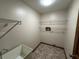 Bright laundry room includes a utility sink, overhead shelving, and ceramic tile flooring at 1811 Springwood Ln, Deltona, FL 32725