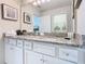 Bathroom featuring granite counters, double sinks, and white cabinets at 201 Jetty Way, Davenport, FL 33897