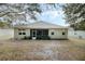 Rear exterior view of the home showing the screened patio and the expansive yard, framed by mature trees at 3289 Saloman Ln, Clermont, FL 34711