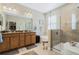 Modern bathroom featuring a double vanity, soaking tub, glass-enclosed shower, and neutral tile flooring at 3289 Saloman Ln, Clermont, FL 34711