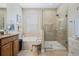 Elegant bathroom featuring a soaking tub, glass-enclosed shower, neutral tile, and stylish vanity at 3289 Saloman Ln, Clermont, FL 34711