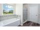 Bright bathroom featuring a bathtub, a glass-enclosed shower, and a window at 4898 Lyric Dr, Mascotte, FL 34753