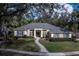 Stunning single-story home with brick walkway, lush landscaping, and blue shutters, framed by mature trees and a blue sky at 4978 Fawn Ridge Pl, Sanford, FL 32771