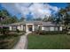 Inviting one-story home with a brick walkway, lush landscaping, and blue shutters, all under a bright, partly cloudy sky at 4978 Fawn Ridge Pl, Sanford, FL 32771