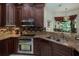 Well-equipped kitchen featuring granite countertops, dark cabinets, stainless steel appliances and mosaic backsplash at 4978 Fawn Ridge Pl, Sanford, FL 32771