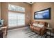 Cozy sitting room with a brown leather sofa, blue area rug and natural light from the large window at 4978 Fawn Ridge Pl, Sanford, FL 32771