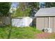 A view of the backyard showing sheds, overgrown grass, and air conditioning units at 5433 Vanderlin St, Orlando, FL 32810