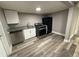 Kitchen featuring stainless steel dishwasher, black refrigerator, granite countertops, laminate flooring, and white cabinets at 5433 Vanderlin St, Orlando, FL 32810