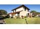 Well-manicured lawn surrounds the side of the house that shows a red tiled roof and tan exterior walls at 549 Hunter Cir, Kissimmee, FL 34758