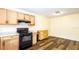 Well-lit kitchen with black appliances, natural wooden cabinets, a white countertop and hardwood floors at 549 Hunter Cir, Kissimmee, FL 34758