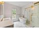 Luxurious bathroom featuring marble-style walls and floors, with a glass-enclosed shower, soaking tub, and vanity at 6229 Indian Meadow St, Orlando, FL 32819