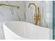 A luxurious white soaking tub featuring gold hardware and a handheld shower head with beautiful marble walls at 6229 Indian Meadow St, Orlando, FL 32819