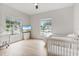 Bedroom features wood floors, a ceiling fan, a bright window, and is staged with modern furniture and a crib at 6229 Indian Meadow St, Orlando, FL 32819