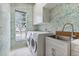 Laundry room with palm-themed wallpaper, window, modern washer/dryer, and utility sink with wooden countertop at 6229 Indian Meadow St, Orlando, FL 32819