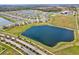 An aerial view showcasing a residential community near a sizable pond and recreational fields at 64 Citrine Loop, Kissimmee, FL 34758