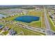 Aerial perspective of homes near a large, dark pond alongside a well-maintained roadway and school at 64 Citrine Loop, Kissimmee, FL 34758