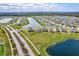 Expansive aerial view of a community showcasing houses near a lake on well-maintained, lush green lawns at 64 Citrine Loop, Kissimmee, FL 34758