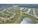 Sprawling aerial shot of a residential area with a pond, featuring multiple homes and manicured lawns at 64 Citrine Loop, Kissimmee, FL 34758