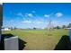 Back yard view with A/C unit, lush lawn, small tree, and lake in the distance on a sunny day at 64 Citrine Loop, Kissimmee, FL 34758