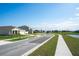 Street view featuring suburban home exteriors with lush green lawns, and a lake in the distance at 64 Citrine Loop, Kissimmee, FL 34758