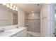 Bathroom showcasing double sinks, a large mirror, and a shower with gray and white tiles at 6627 Lullaby Way, Mascotte, FL 34753