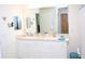 Bright bathroom featuring double sinks, a large mirror, and white cabinets at 6910 Se 111Th Pl, Belleview, FL 34420