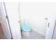 Bright toilet room with a toilet that has a blue seat, gray floors, and white walls at 6910 Se 111Th Pl, Belleview, FL 34420