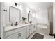 Bathroom with double vanity, white cabinets, modern fixtures, and a soaking tub at 704 Hyperion Dr, Debary, FL 32713