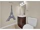 Half bath featuring a vanity sink and a toilet, highlighted with a mural of the Eiffel Tower at 7448 Grand Ct, Winter Park, FL 32792