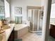 Bathroom featuring double vanity, soaking tub, glass shower, earth toned tiled floors and coordinated bath towels at 8744 Currituck Sound Ln, Orlando, FL 32829