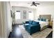 Bright bedroom with a blue sofa, tufted headboard bed, and natural light from the large windows at 8744 Currituck Sound Ln, Orlando, FL 32829