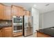 Close-up of the kitchen appliances, including a stainless steel refrigerator and built-in oven with wood cabinets at 981 Galway Blvd, Apopka, FL 32703