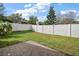 A charming backyard features a white privacy fence, green grass, and a small brick patio on a sunny day at 1061 New Castle Ln, Oviedo, FL 32765