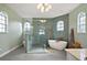 Modern bathroom featuring a glass-enclosed shower, soaking tub, unique tile, and stylish arched windows at 1061 New Castle Ln, Oviedo, FL 32765