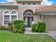 Inviting front entryway features a decorative glass door, manicured shrubs, and a well-maintained lawn at 11327 Ledgement Ln, Windermere, FL 34786