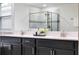 Bathroom featuring double sinks with modern faucets and vanity with black cabinets and a glass enclosed shower at 11381 Satire St, Orlando, FL 32832