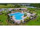 Aerial view of a large community pool surrounded by palm trees and lounge chairs, with a clubhouse in the background at 11381 Satire St, Orlando, FL 32832