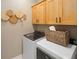 This laundry room has side-by-side washing machine and dryer, light wood cabinets, neutral walls and floor at 12471 Shipwatch St, Orlando, FL 32832