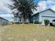 Quaint one-story home with inviting curb appeal, featuring a mature tree and a charming porch swing at 233 Ashley Loop, Davenport, FL 33837