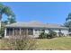 Spacious rear exterior featuring a screened-in porch, well manicured lawn, and lush landscaping at 2628 Caribe Dr, The Villages, FL 32162