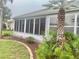 Enclosed sunroom with multiple windows, complemented by tropical landscaping and a mature palm tree at 2628 Caribe Dr, The Villages, FL 32162