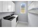 Functional laundry room with white cabinets, modern washer and dryer, and a window for natural light at 3029 Ambersweet Pl, Clermont, FL 34711