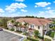 Exterior of a beige two-story townhome with a brown roof, palm trees, and parking spaces at 3204 Gold Ln, Kissimmee, FL 34747