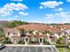 Exterior of a beige two-story townhome with a brown roof, palm trees, and parking spaces at 3204 Gold Ln, Kissimmee, FL 34747