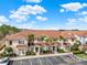 Exterior of a beige two-story townhome with a brown roof, palm trees, and parking spaces at 3204 Gold Ln, Kissimmee, FL 34747