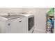 Laundry room with a washing machine, dryer, and storage rack with cleaning supplies at 3871 Brant Pl, Leesburg, FL 34748