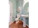 Charming half bathroom features a pedestal sink, wood flooring, and seashell decor at 4268 Ethan Ln, Orlando, FL 32814